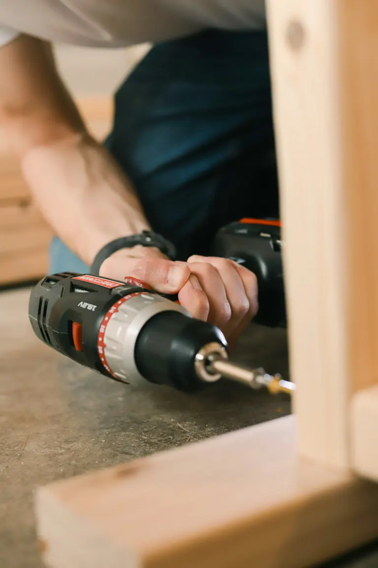 A cordless drill being held ready for furniture assembly work.