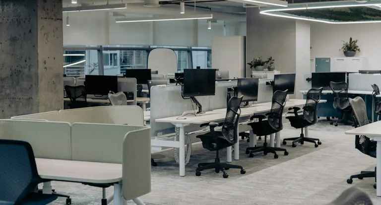 An office with multiple desks and chairs arranged for work.